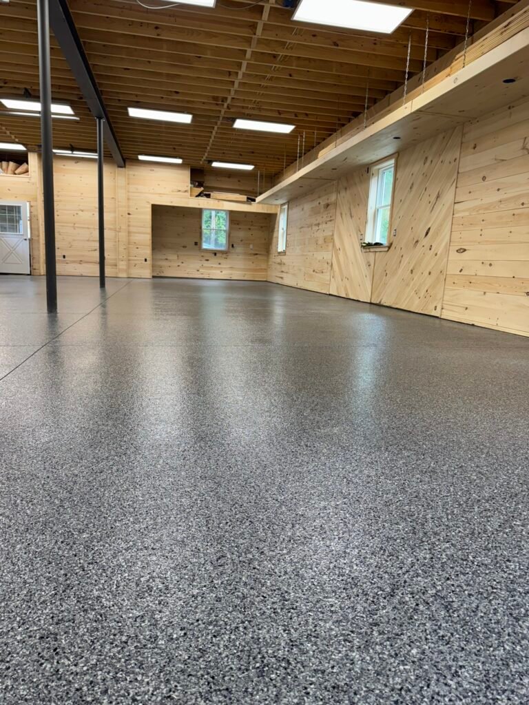 Finished garage floor coated with charcoal-gray polyaspartic flake system, UV-stable and seamless finish by Flake Pro Coatings.