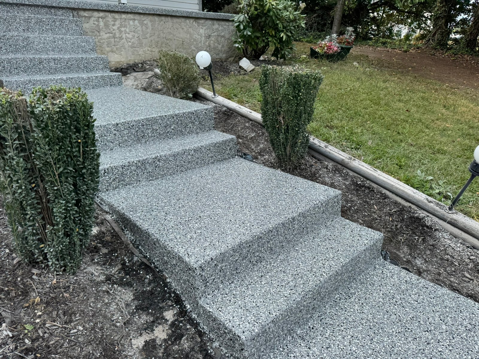 Residential walkway coated with beige polyaspartic flake system surrounded by greenery