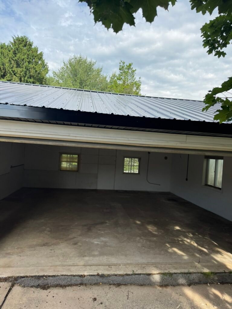 Bare gray concrete garage floor before polyaspartic coating, garage door open to driveway