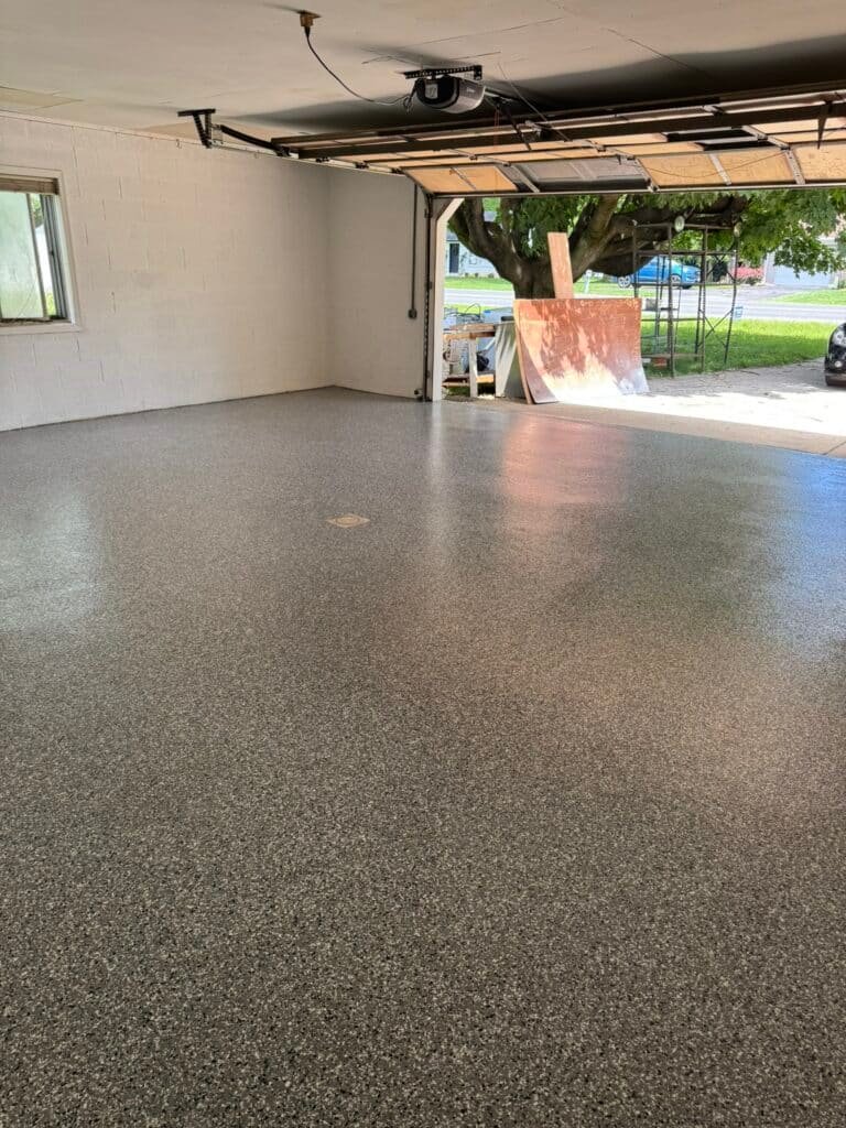 Charcoal and white flake garage floor coating viewed toward open garage door