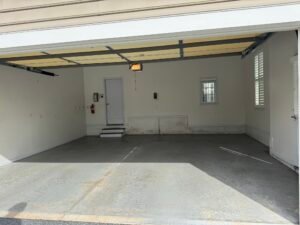 Bare gray concrete garage floor before polyaspartic coating, fire extinguisher on wall