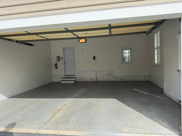 Bare gray concrete garage floor before polyaspartic coating, fire extinguisher on wall