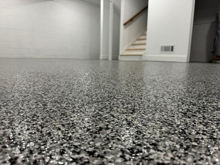 Dark gray, black and white flake basement floor coating with staircase in background