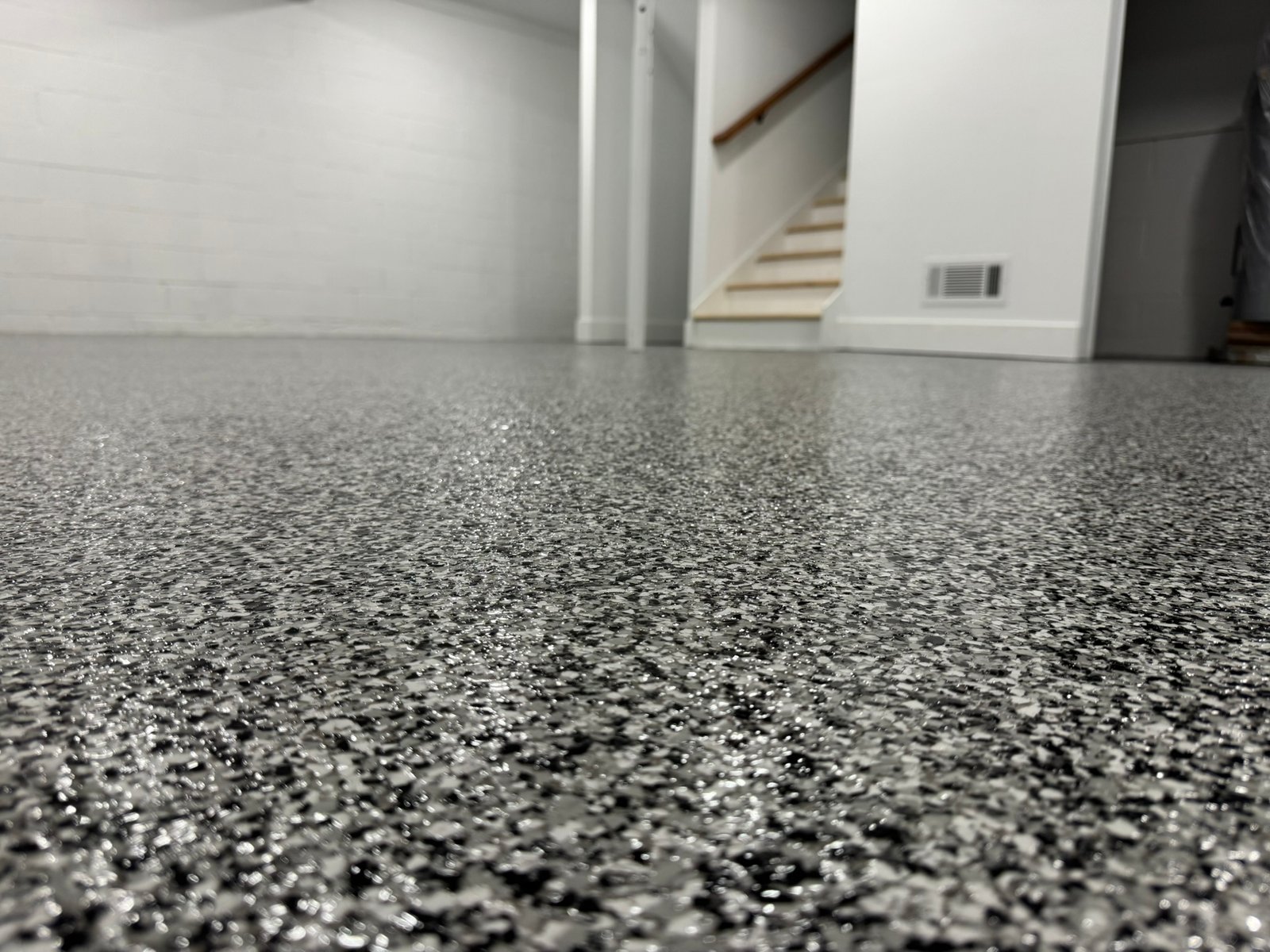 Dark gray, black and white flake basement floor coating with staircase in background
