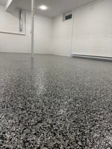 Dark gray, black and white flake basement floor coating, wide view of finished basement