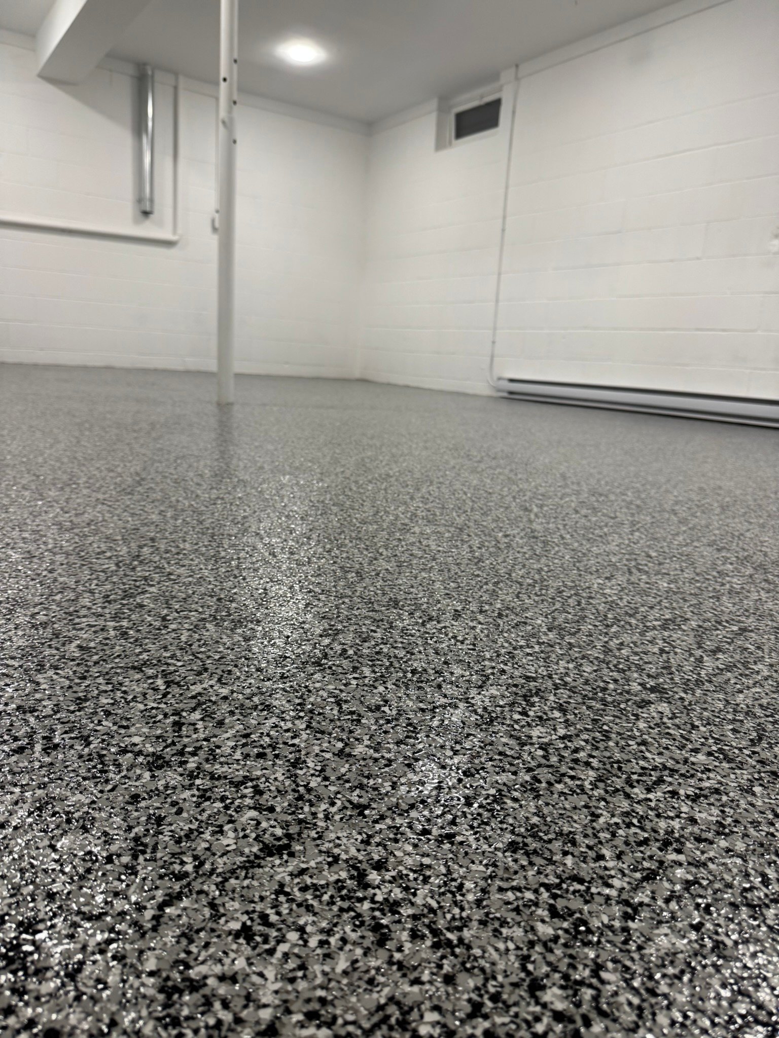 Dark gray, black and white flake basement floor coating, wide view of finished basement