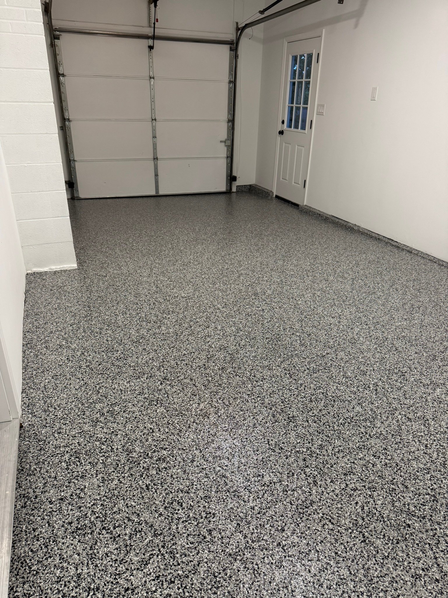 Black, gray and white flake polyaspartic garage floor coating after installation