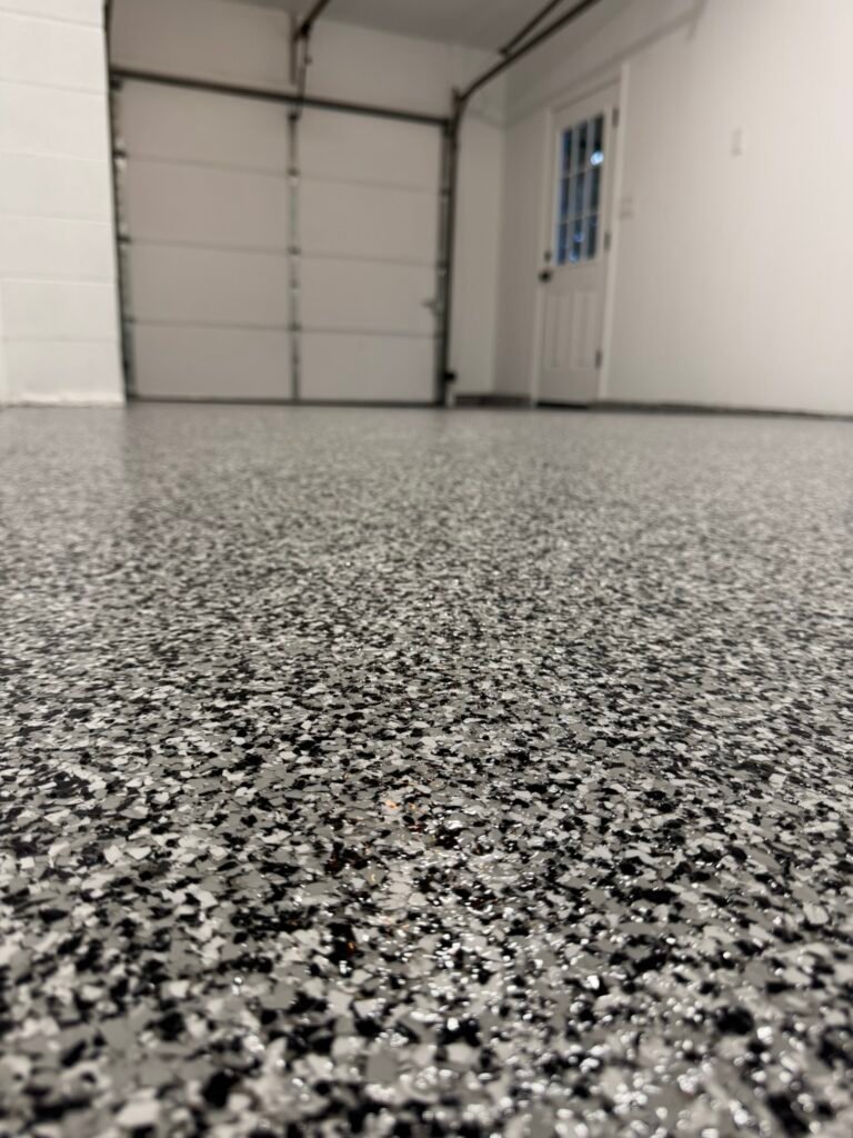 Black, gray and white flake garage floor coating near interior door