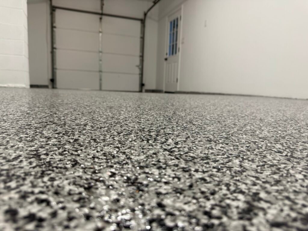Black, gray and white flake garage floor coating near glass door