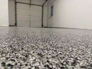 Black, gray and white flake garage floor coating near glass door