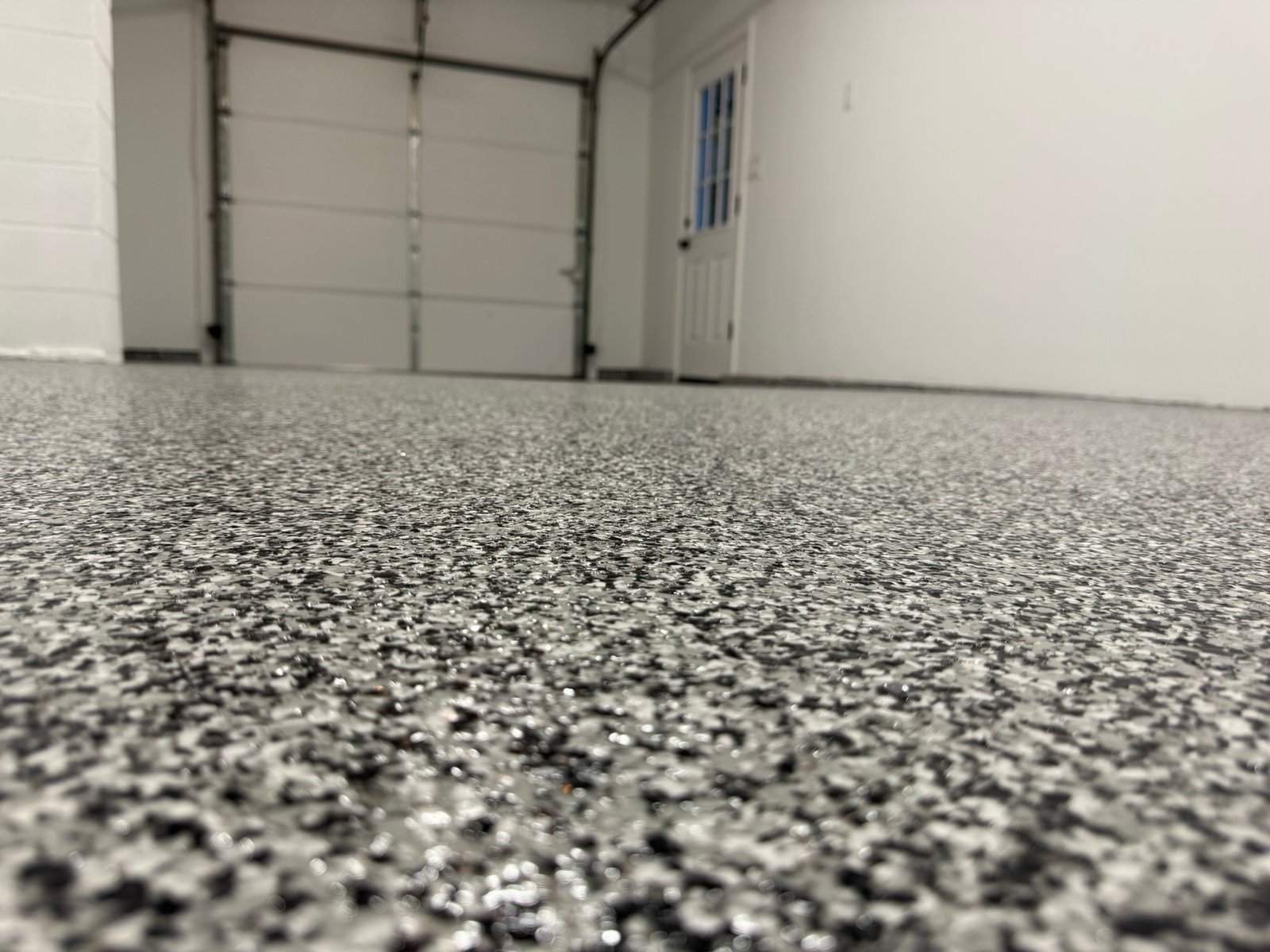 Black, gray and white flake garage floor coating near glass door