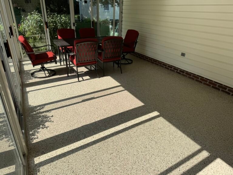 Furnished sunroom with patio table and red cushioned chairs on flake-coated floor