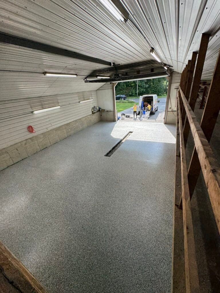 Gray, black and white flake pole-barn floor coating, crew and branded van at open door