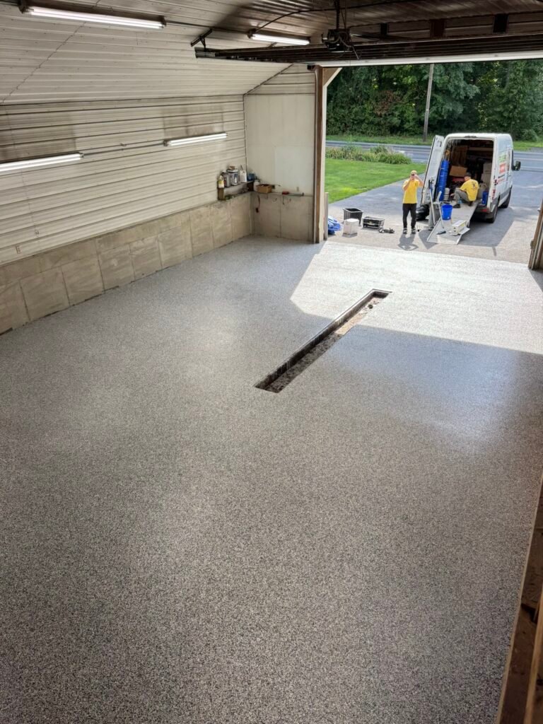 Gray, black and white flake floor coating in pole-barn building, crew loading branded van outside