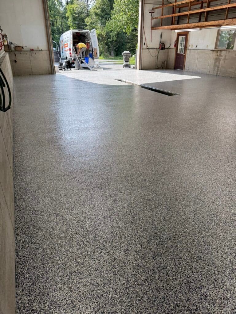 Gray, black and white flake pole-barn floor coating near open bay door