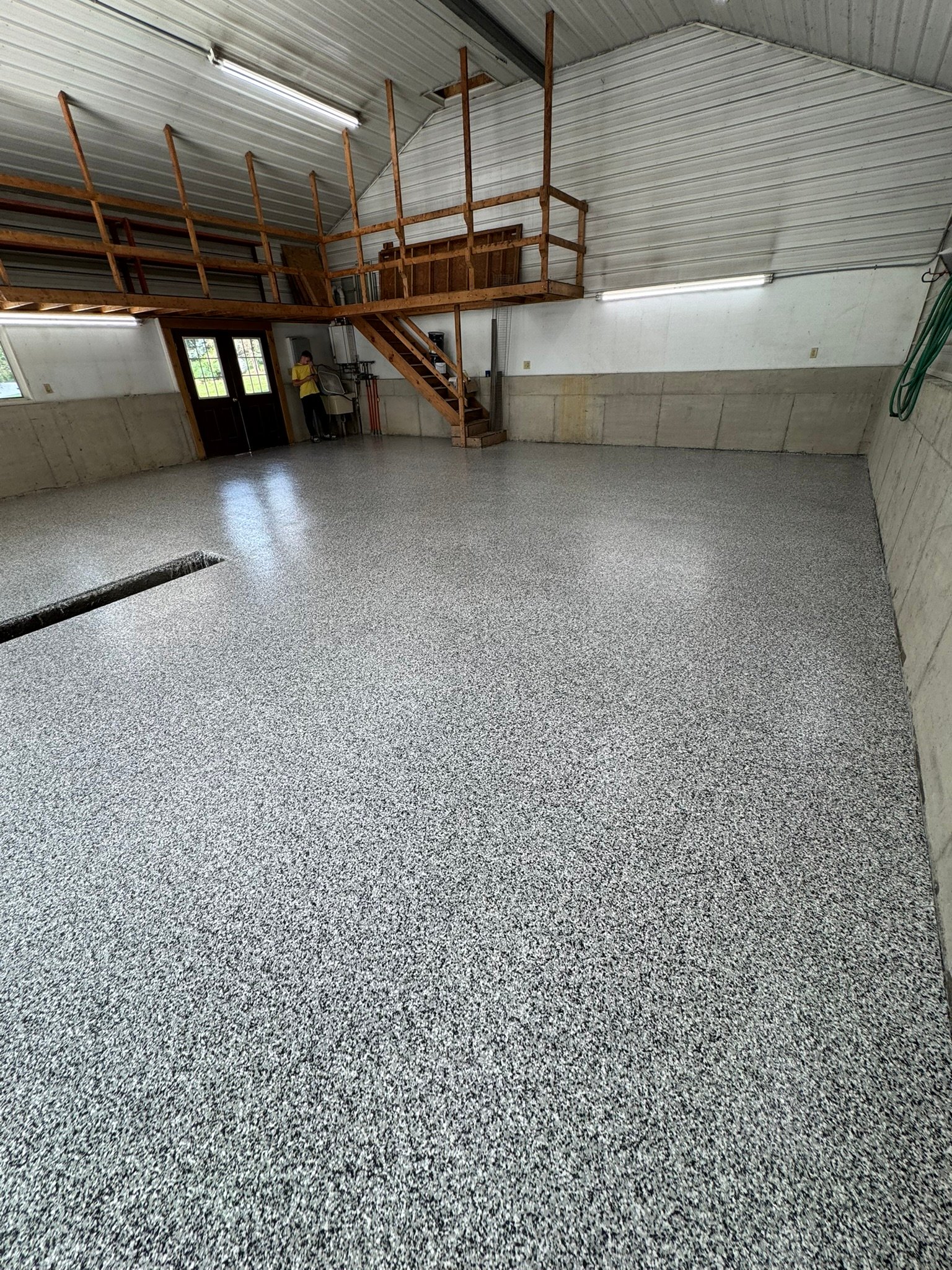 Wide view of finished gray, black and white flake pole-barn floor coating with mezzanine