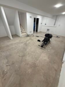 Bare concrete basement floor with staircase before floor coating