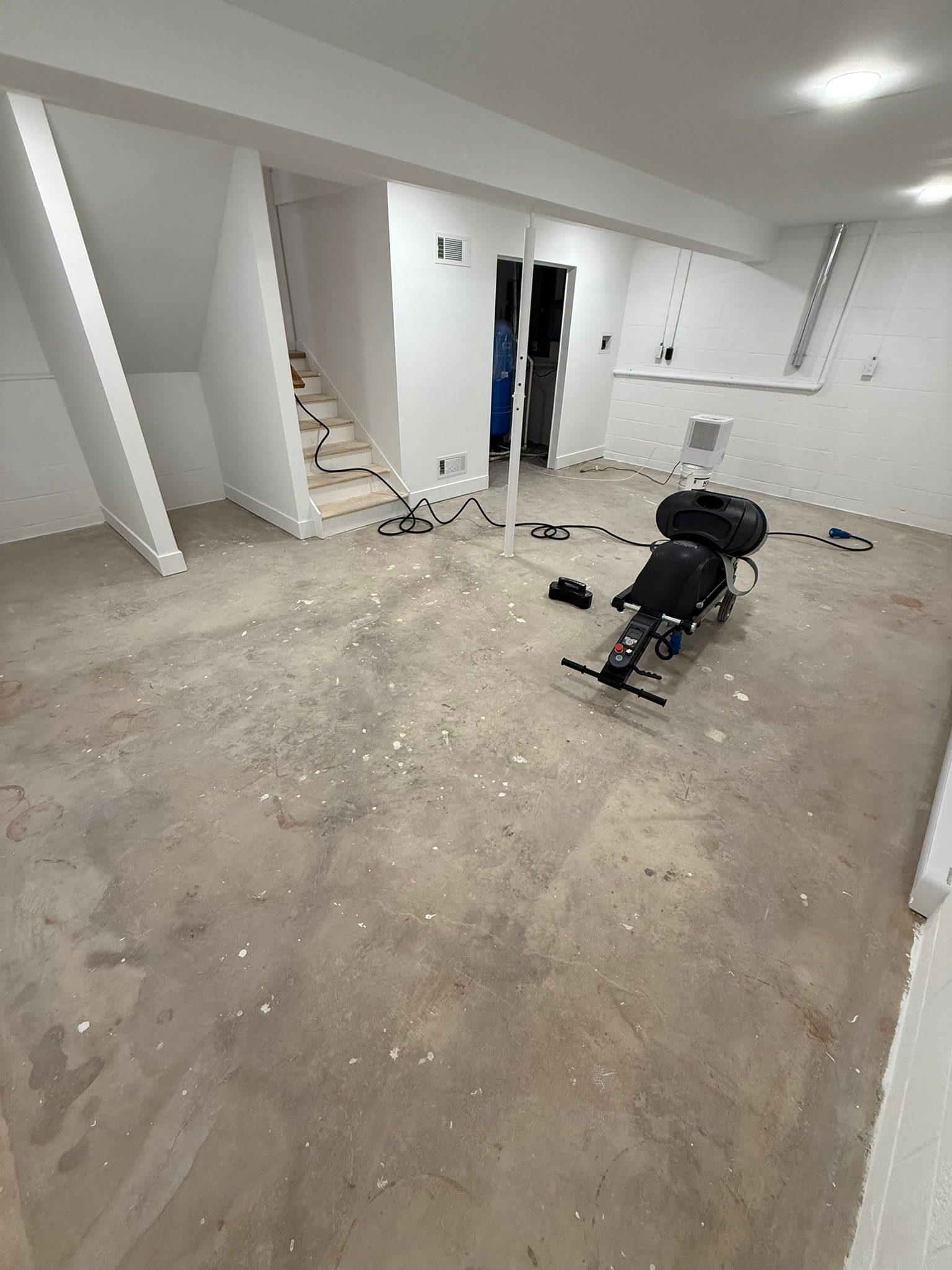 Bare concrete basement floor with staircase before floor coating