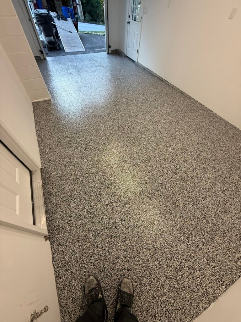 Gray, black and white flake garage floor coating with view toward driveway