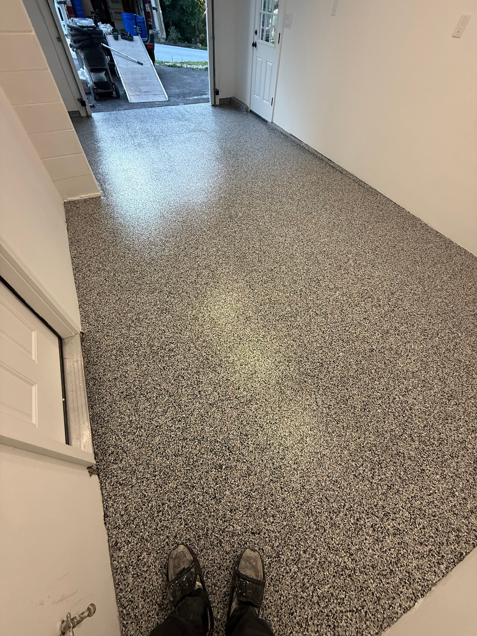 Gray, black and white flake garage floor coating with view toward driveway