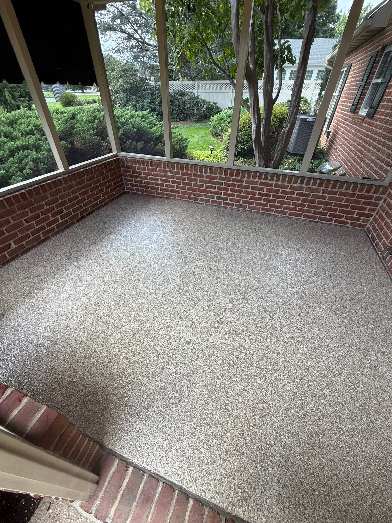 Tan, beige, black and white flake screened porch floor coating with brick knee walls